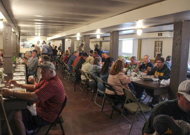 ["The Swiss community of Helvetia, West Virginia began hosting its annual ramp supper sometime between 1946-1948 (Helvetia native Ernest Hofer who has been working at the supper for at least 40 years, wasnt sure of the exact date). The event is a fundraiser, benefiting the Helvetia Community Hall Association and the Farm Womens Club. For weeks prior, volunteers, including local 4-H kids, work to wash and freeze 60 bushels of ramps, some of which are dug and donated by locals, and the rest are bought from a digger. On the Friday before the event, male volunteers gather outside to cook 400 lbs. of potatoes in iron kettles over a wood fire, while drinking homemade wine. Women volunteers work in the kitchen, cutting 300 lbs. of ham, making cornbread, cooking Navy beans, and defrosting ramps. The Helvetia Ramp Supper is always held the last Saturday in April and draws visitors from across the state and region. The dinner includes fried and fresh ramps, beans, ham, fried potatoes, applesauce, cornbread, coleslaw, drink, and dessert, which guests eat at long tables in the basement of the Helvetia Community Hall. After dinner, a square dance is held upstairs. The documentation of the Helvetia Ramp Supper is part of the Helvetia Foodways Oral History Project in partnership with the Southern Foodways Alliance. Learn more: https://www.southernfoodways.org/oral-history/helvetia-west-virginia/Also see Emily Hilliards piece on Helvetias seasonal celebrations, including the Ramp Supper, via The Bitter Southerner: https://bittersoutherner.com/my-year-in-helvetia-west-virginia and read her piece on the Ramp Supper via the West Virginia Folklife blog: https://wvfolklife.org/2016/05/27/rampfingerprints/For more information, visit: http://www.helvetiawv.com/Events/Helvetia_Ramps/Helvetia_Ramps.htm"]%