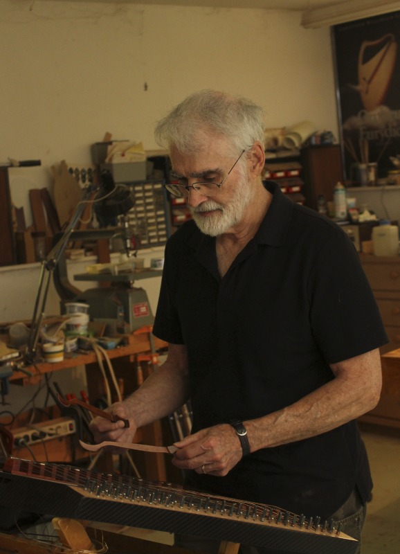 Sam Rizzetta is a dulcimer designer, builder, and musician who moved to West Virginia in the early 1970s. He was a member of the string band Trapezoid and founded the hammer dulcimer playing classes at the Augusta Heritage Center at Davis & Elkins College. He has built dulcimers for musicians including John McCutcheon, Guy Carawan, and Sam Herrmann. Rizzetta now collaborates with the Dusty Strings Company who build hammer dulcimers based on his designs. He lives with his wife Carrie Rizzetta in Berkeley County, WV. He was photographed in his home workshop.