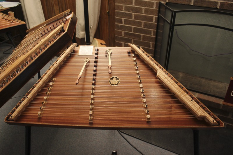 ["Wooden hammer dulcimer made by Sam Rizzetta. Rizzetta is a dulcimer designer, builder, and musician who moved to West Virginia in the early 1970s. He was a member of the string band Trapezoid and founded the hammer dulcimer playing classes at the Augusta Heritage Center at Davis & Elkins College. He has built dulcimers for musicians including John McCutcheon, Guy Carawan, and Sam Herrmann. Rizzetta now collaborates with the Dusty Strings Company who build hammer dulcimers based on his designs. He lives with his wife Carrie Rizzetta in Berkeley County, WV. He was photographed in his home workshop."]%