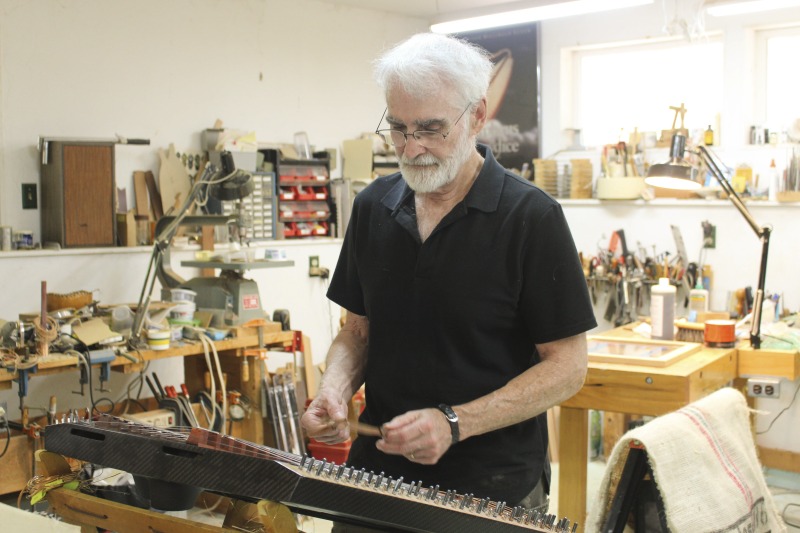 Sam Rizzetta is a dulcimer designer, builder, and musician who moved to West Virginia in the early 1970s. He was a member of the string band Trapezoid and founded the hammer dulcimer playing classes at the Augusta Heritage Center at Davis & Elkins College. He has built dulcimers for musicians including John McCutcheon, Guy Carawan, and Sam Herrmann. Rizzetta now collaborates with the Dusty Strings Company who build hammer dulcimers based on his designs. He lives with his wife Carrie Rizzetta in Berkeley County, WV. He was photographed in his home workshop.