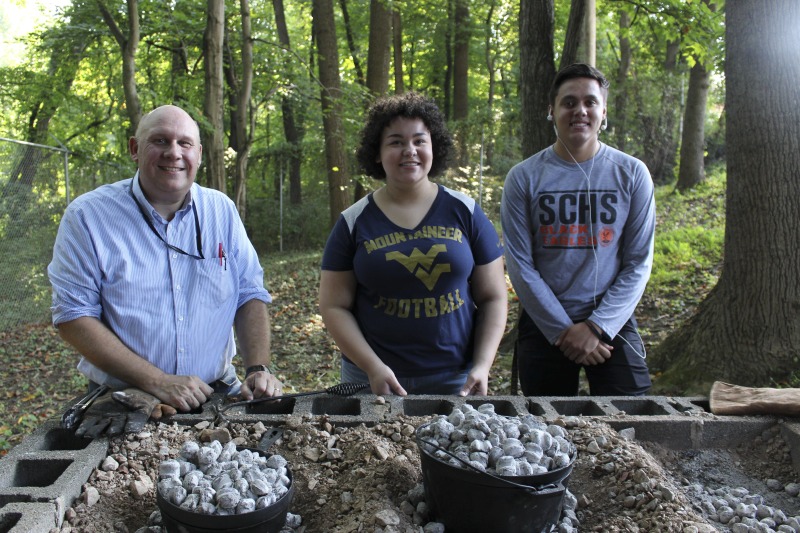 ["On September 21, 2017, old-time musician and writer Pete Koskys Appalachian Studies class at South Charleston High School made biscuits in a cast iron Dutch oven over a charcoal fire at the ROTC picnic shelter on the school campus. Kosky invited state folklorist Emily Hilliard to the class."]%