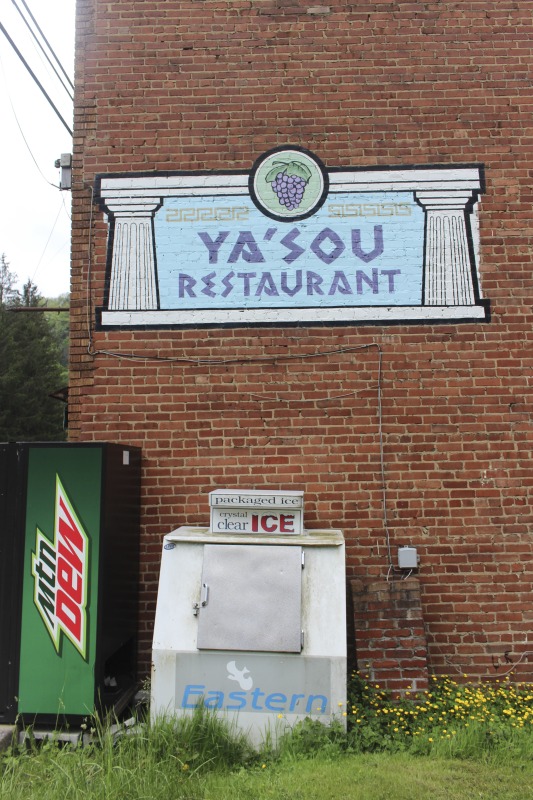 Yasou Restaurant is a Greek restaurant and grocery in Kimball in McDowell County. The restaurant has been owned and operated since 2003 by Markella Gianato whose maternal grandfather John Genadopoulus and father Adamantios Tommy Balasis opened The West Virginia Grocery in the same location in 1947. Genadopolous bought the building from A.P. Wood, whose name still remains on the storefront. The Grocery shut down in 2001 after the July flood all but destroyed the building.Today the restaurant serves as a hub in the Kimball community. Menu offerings include gyros, Greek-style spaghetti and meatballs, spanakopita, Greek salad, pastitsio (a Greek pasta with meat and bchamel), dolmades (stuffed grape leaves), and saganaki (pan-seared Greek cheese).State folklorist Emily Hilliard interviewed Gianato about her family history, foodways, and the business on April 27, 2016, but the interview was lost when Folklife Program equipment was stolen. Gianatos Our History statement on the Yasou website:On February 7, 1947, the Greek-American families of John Genadopoulos and Adamantios Tommy Balasis and Mary Balasis purchased the A.P. Wood Grocery.  Though the store was renamed the West Virginia Grocery, the name A.P. Wood remains etched in beautiful stained glass over the door at present day YaSou. From that time until the devasting flood of July 2001, the family kept the grocery in operation.  Ten months later, a second major flood hit the town within days of the business being reopened.  Despite this major setback, we were determined to move forward and reopen the business. Having my own restaurant was a lifelong dream, and on February 7, 2003, with the help of my mother Mary Balasis, my brothers John and Mathew, my husband Jimmy Joe, my son Adam, my mother-in-law Mary Verduce Gianato and the Grace of God, that dream became a reality with the opening of YaSou Restaurant.   I am immensely proud of the success that I have achieved.  I offer home-cooked meals, daily specials, and Greek cuisine along with many sandwich choices.  Most of the recipes I have used have been handed down to me from my mother and grandmother.  My love for the restaurant business came from my first job at the Virginian Restaurant in Pearisburg, Virginia, working under the guiding hands of, in my opinion, two of the greatest chefs, uncles and mentors, Mike and George Genadopoulos.  It was my days at the Virginian that made me realize I would someday like to become a great chef.  I strive for this every day. This has allowed me to meet many wonderful people who have stopped in along the way, as well as many local regulars who come in and make my day complete.  We hope to serve you for many years to come. Everyone that comes here, even for one time, becomes a part of the labyrinth of my life and will always be part of the memories here.  I want my guests to feel at home and comfortable when that are here.  If you have any concerns or requests, please feel free to ask.                                                             ---MarkellaRead more on the Yasou website: https://yasourestaurant-restaurant.business.site/